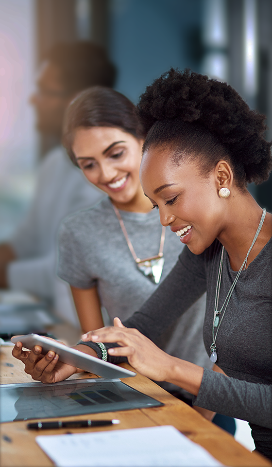 Deux femmes souriantes regardant un iPad