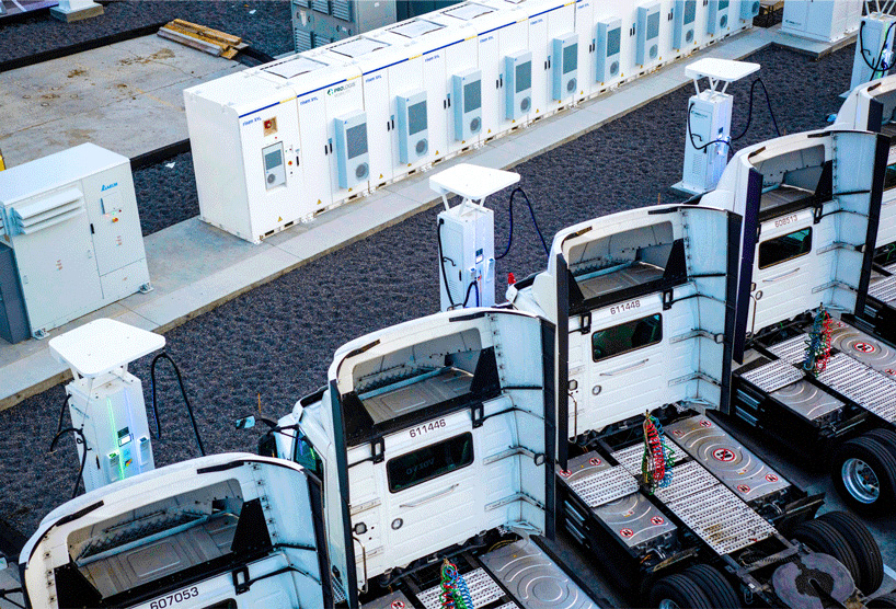 Des camions semi-remorques électriques chargent devant un entrepôt Prologis