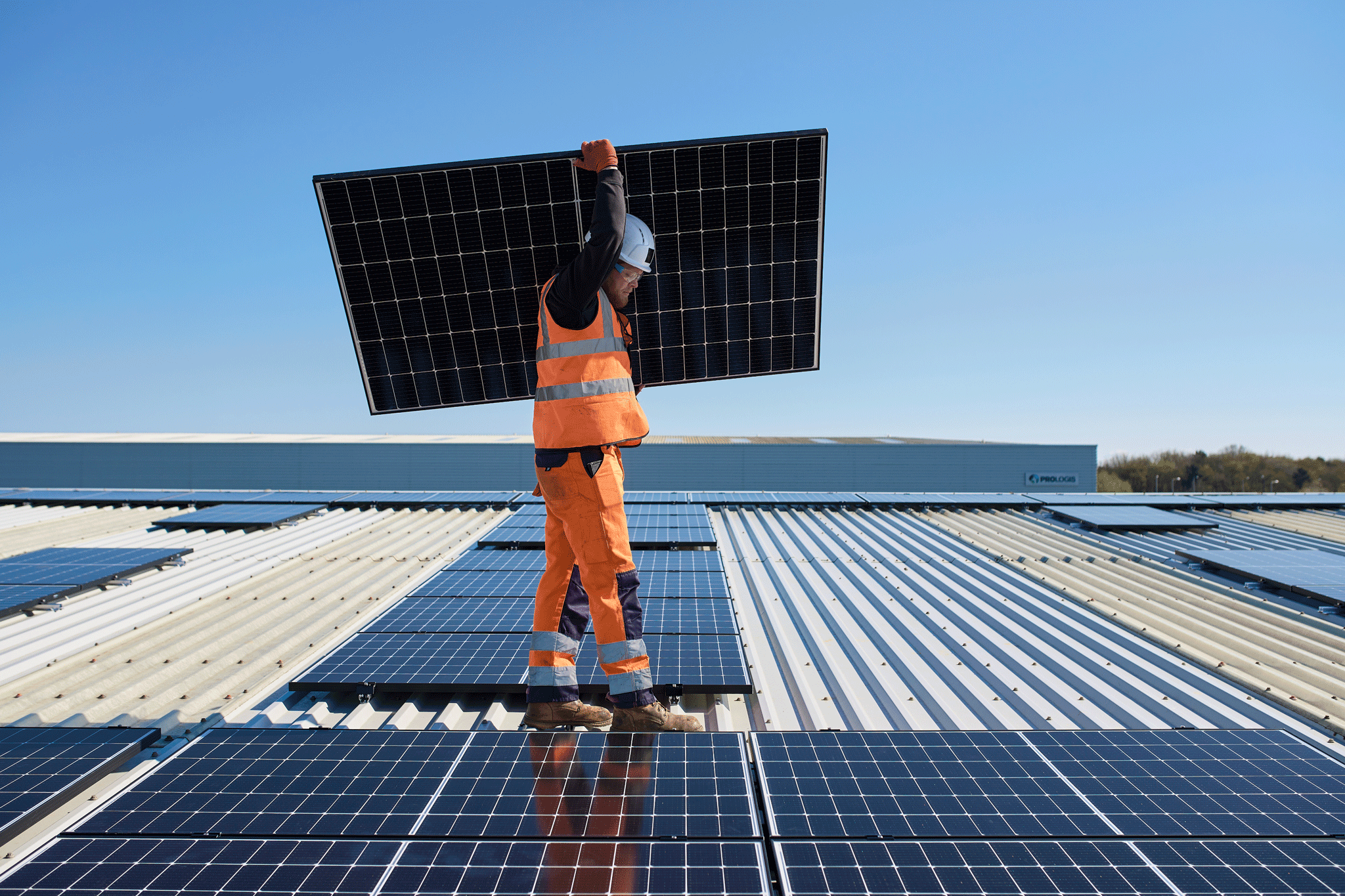 Une personne sur un toit porte un panneau solaire